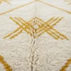 Détail de la laine ivoire et du motif géométrique ocre doré du tapis Azilal